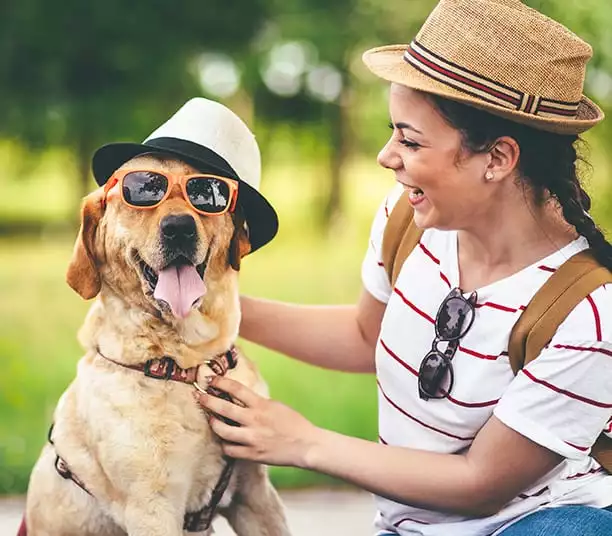 woman dresses dog in sun hat and glasses